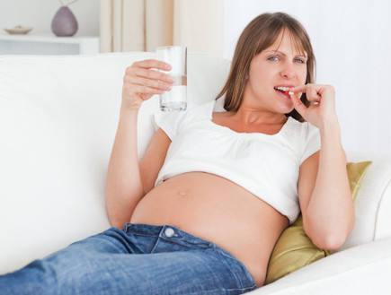 אישה בהריון לוקחת תרופה מחזיקה כוס מים (צילום: אימג'בנק / Thinkstock)