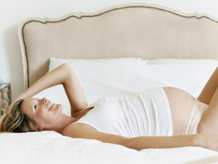 אישה בהריון שוכבת על הגב מניחה יד על ראשה (צילום: אימג'בנק / Thinkstock)