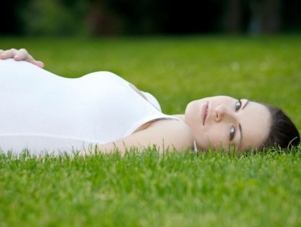 אישה בהריון שוכבת על הדשא (צילום: אימג'בנק / Thinkstock)