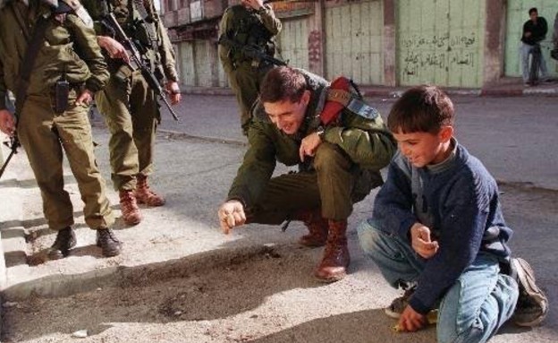 חייל משחק עם ילד פלסטיני