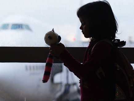 ילדה עם בובה על רקע שדה התעופה (צילום: איתי תורג'מן)