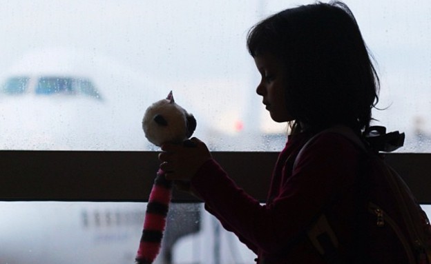 ילדה עם בובה על רקע שדה התעופה (צילום: איתי תורג'מן)