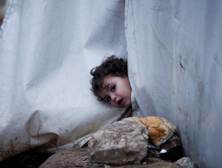 ילדה מציצה בין הריסות (צילום: AP Photos/ Manu Barbo)