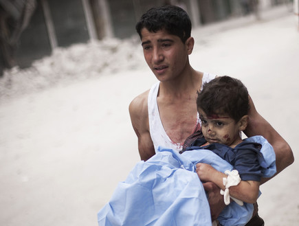 נער מפנה ילד פצוע בסוריה (צילום: AP Photos/ Manu Brabo)