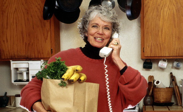 אישה מחזיקה קניות ומדברת בטלפון