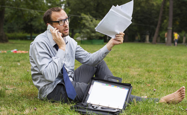 איש מדבר בטלפון בפארק עם תיק מסמכים (צילום: אימג'בנק / Thinkstock)