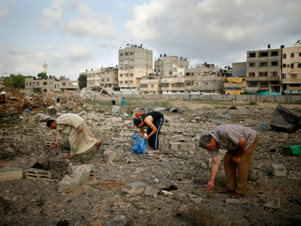 פלסטינאים מחפשים חלקי גופות בהריסות בעזה (צילום: רויטרס)
