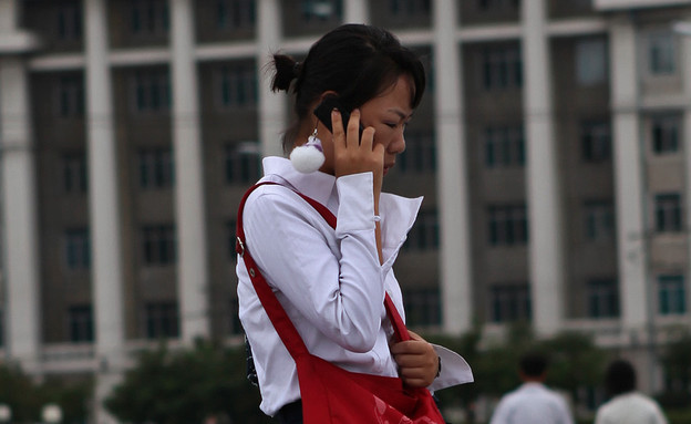 אישה בקוריאה הצפונית מדברת בטלפון סלולרי (צילום: Roman Harak, Flickr)