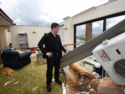 תושב בריסביין בוחן את נזקי הסופה בביתו (צילום: AP)