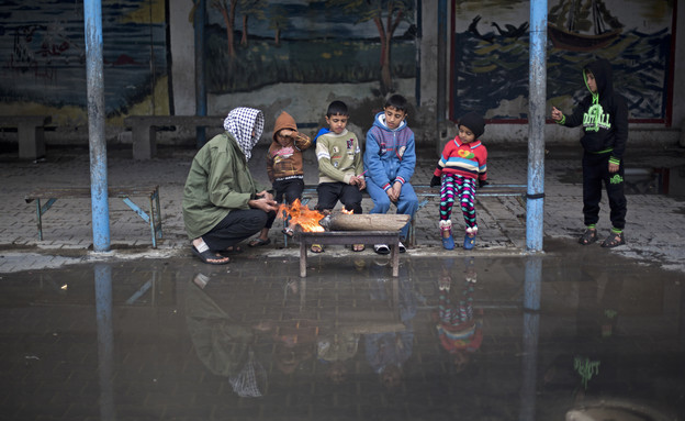 פלסטינים שבתיהם נהרסו במבצע צוק איתן מתחממים מול מדורה ברחוב בעזה (צילום: ap)