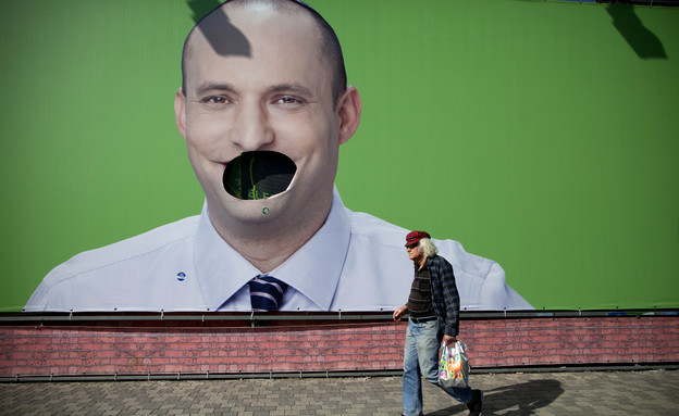 איש הולך מול שלט בחירות של נפתלי בנט שהושחת (צילום: ap)