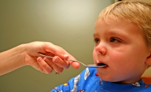 ילד חולה עם כפית בפה (צילום: DIGIcal, Istock)