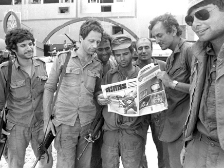 חיילים מביטים בעיתון במחנה (צילום: צלם במחנה)