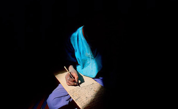 נער כותב לאור צוהר במאלי (צילום: התמונות באדיבות Matjaz Krivic)