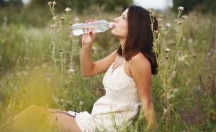 אישה בשדה שותה מבקבוק מים (אילוסטרציה: mikanaka, Thinkstock)