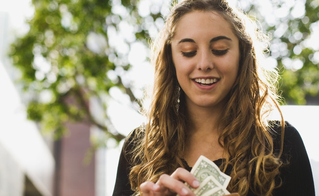 אשה מסתכלת על ארנק מלא בכסף (אילוסטרציה: Brand X Pictures, Thinkstock)