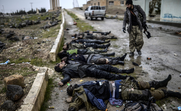 30.1 חייל כורדי לצד גופות של לוחמי דאעש (צילום: אימג'בנק/AFP)