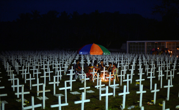1.11 משפחה פיליפינית ליד קבר של אהוב (צילום: אימג'בנק/AFP)