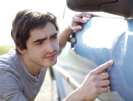 גבר צעיר מסתכל על שריטות על מכונית (אילוסטרציה: pp76, Thinkstock)
