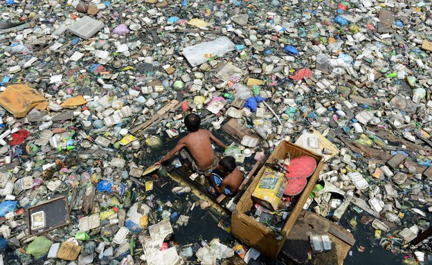 אב ובנו אוספים פלסטיק בפיליפינים (צילום: אימג'בנק/AFP)