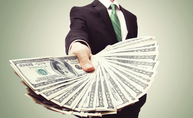 איש עסקים מחזיק חבילת דולרים (אילוסטרציה: Shutterstock)