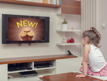 ילדה מסתכלת על פרסומות בטלוויזיה (אילוסטרציה: Shutterstock)