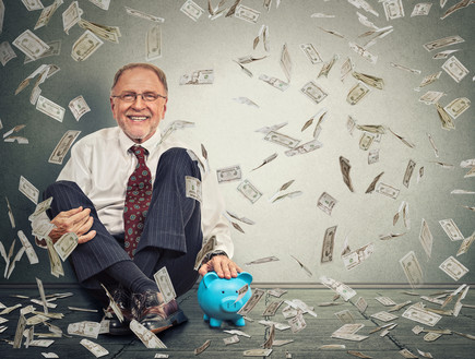 גבר יושב ליד קופת חיסכון תחת גשם של כסף (אילוסטרציה: Shutterstock)