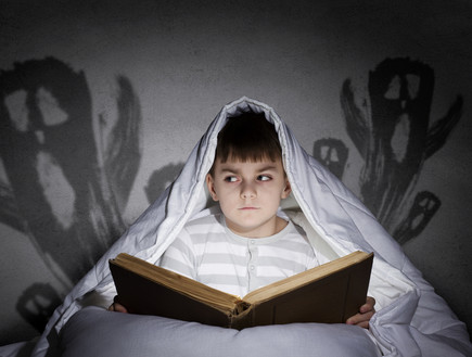 ילד קורא ספר מפחיד (צילום: Shutterstock)