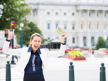 אישה עומדת מול משרדים מחזיקה כסף (אילוסטרציה: Shutterstock)