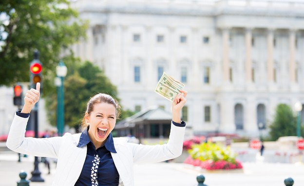 אישה עומדת מול משרדים מחזיקה כסף (אילוסטרציה: Shutterstock)