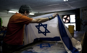 פועל בסדנה לייצור דגלים של קלמן ברמן רקמה ודגלים בירושלים (צילום: יונתן סינדל, פלאש 90)