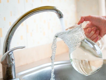אישה ממלאת מים מהברז (אילוסטרציה: Shutterstock)