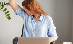 אישה מזיעה במשרד (אילוסטרציה: Shutterstock)