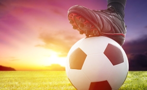 רגל מחזיקה כדורגל על הדשא (צילום: ShutterStock)