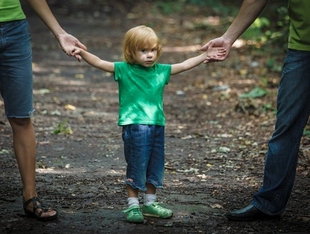ילד מחזיק בידיים של הוריו (אילוסטרציה: Shutterstock)