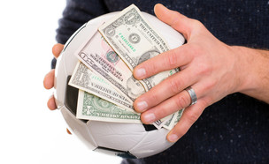 יד מחזיקה כדורגל ושטרות כסף (אילוסטרציה: Shutterstock)