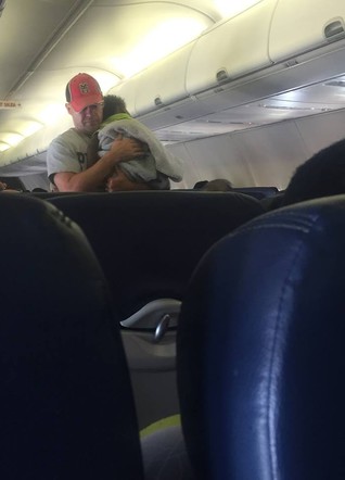 גבר מחזיק תינוק במטוס (צילום: פייסבוק)