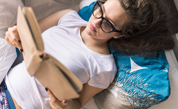 אישה קוראת ספר במיטה (אילוסטרציה: Shutterstock)