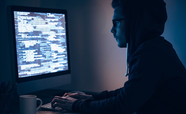 גבר יושב בחושך מול מחשב (צילום: Shutterstock)