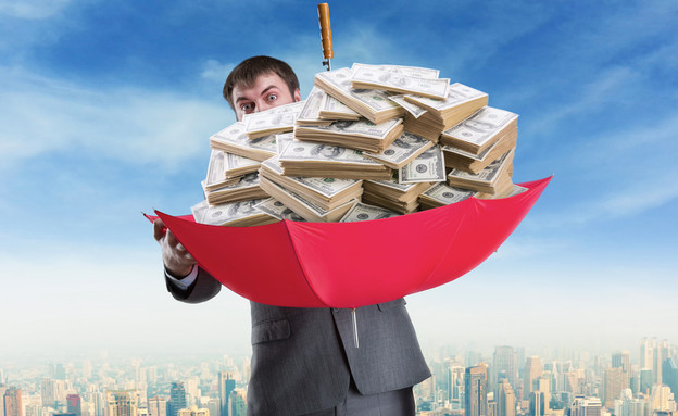 איש עסקים מחזיק ערימה של כסף במטרייה (אילוסטרציה: Shutterstock)