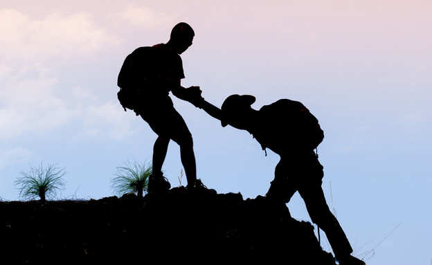 מטייל עוזר לחברו לטפס על הר (צילום: Doidam 10, Shutterstock)