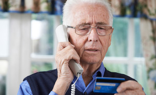 איש מבוגר נותן פרטי אשראי בטלפון (אילוסטרציה: Shutterstock)