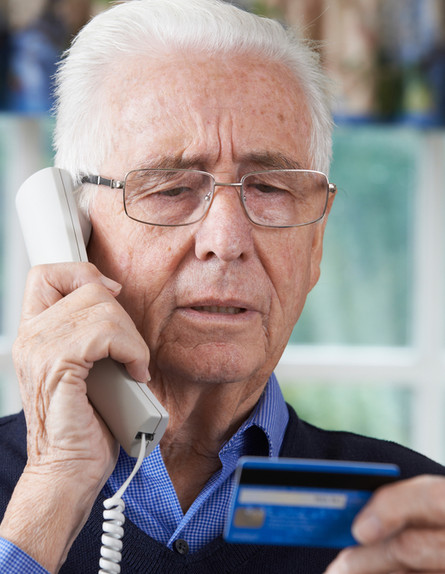 איש מבוגר נותן פרטי אשראי בטלפון (אילוסטרציה: Shutterstock)