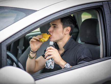 איש אוכל באוטו (צילום: ArtOfPhotos, Shutterstock)
