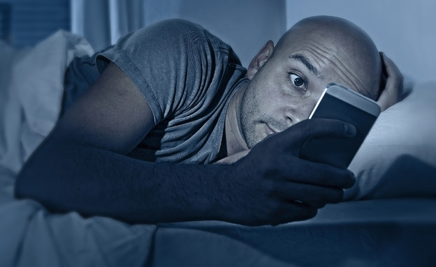 גבר בודק את הסלולרי באמצע הלילה (אילוסטרציה: Shutterstock)