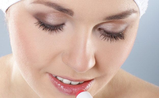 אישה מורחת שפתון לחות (צילום: Maksim Shmeljov, Shutterstock)