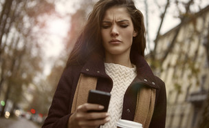 אישה כועסת מסתכלת על הטלפון שלה (אילוסטרציה: Shutterstock)
