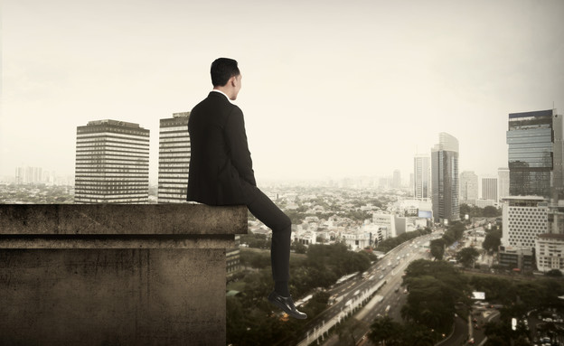 איש עסקים יושב על קצה גג (אילוסטרציה: Shutterstock)