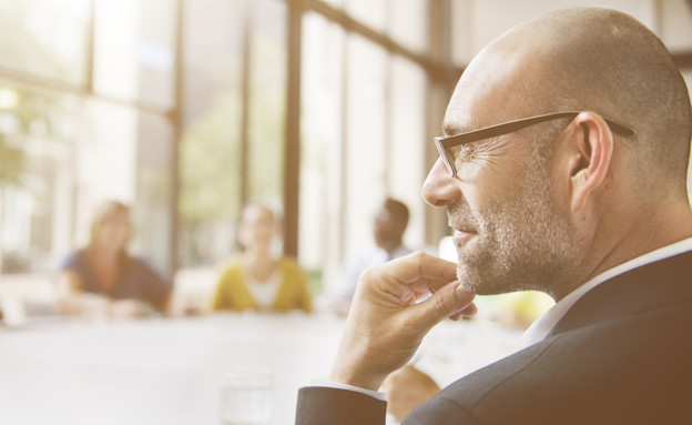איש עסקים מביט לחלון בפגישה (אילוסטרציה: Shutterstock)