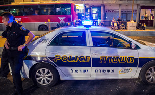 שוטר עומד ליד ניידת משטרה בתל אביב (צילום: Shutterstock)